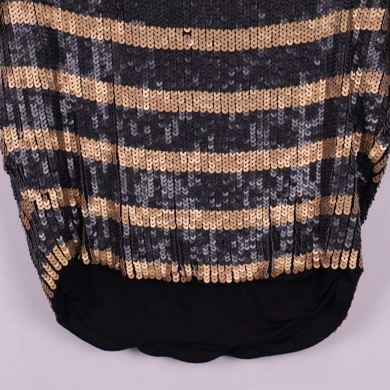 Nederkant på topp med svart tyg och paljettränder ovanför