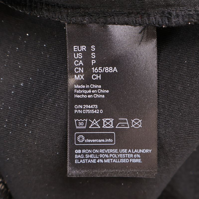 Materialetikett visar 90% polyester, 6% elastan, 4% metallfiber