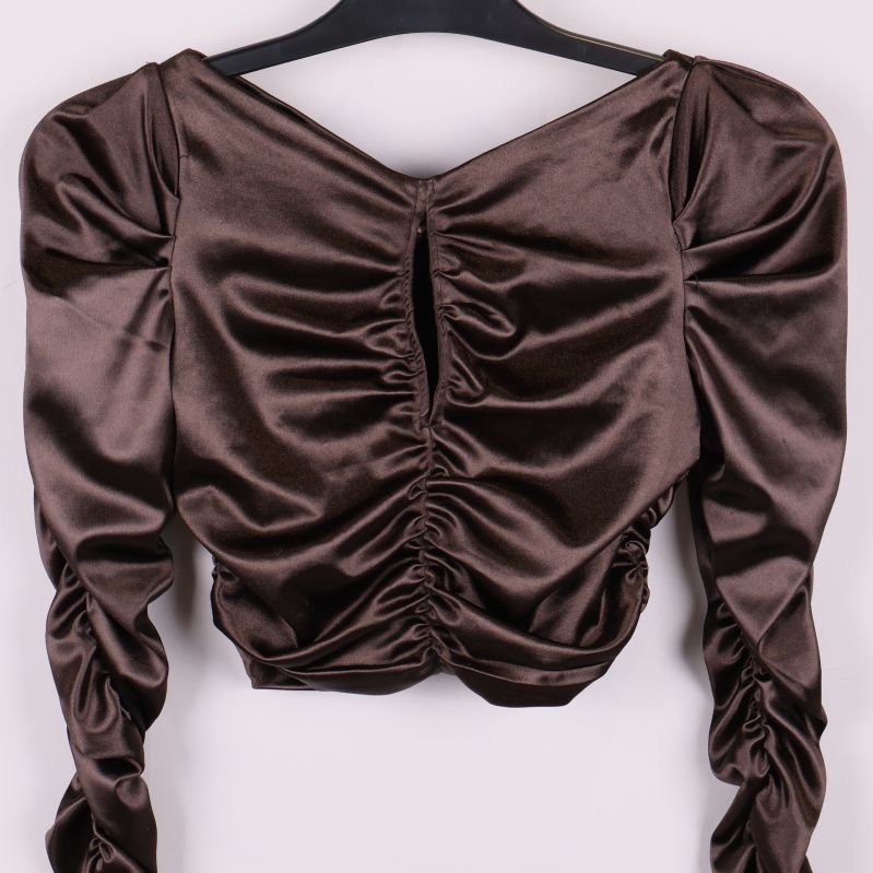Närbild på draperad framsida av brun glansig topp