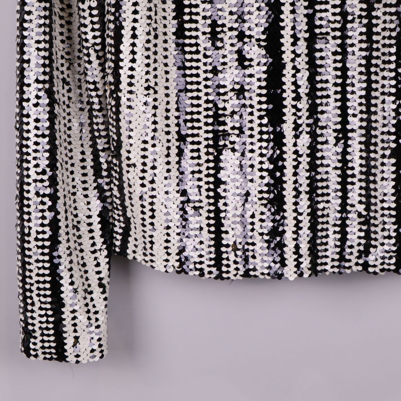 Närbild av ärmslut och paljettmönster på blus