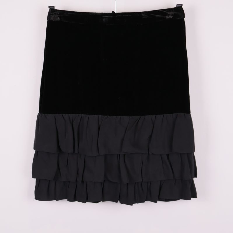 Kort svart kjol med sammetsliv och volanger framtill