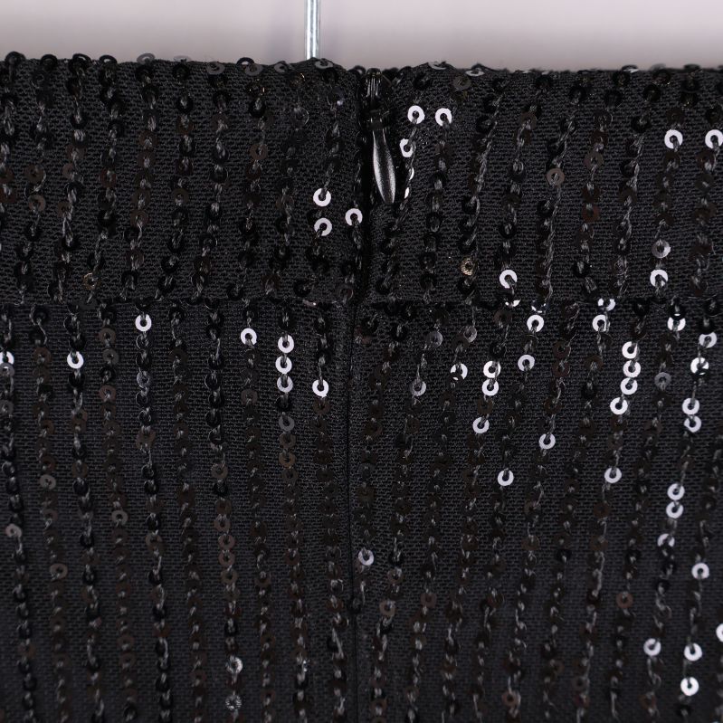 Närbild på dragkedja bak på svart paljettopp