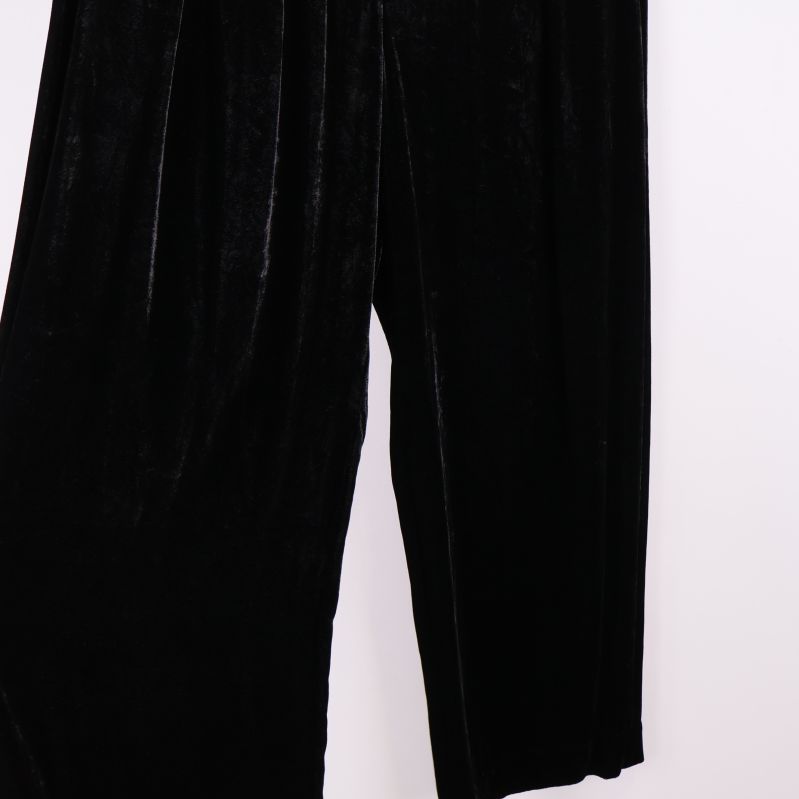 Ben på sammetsbyxor lyfts fram mot vit bakgrund