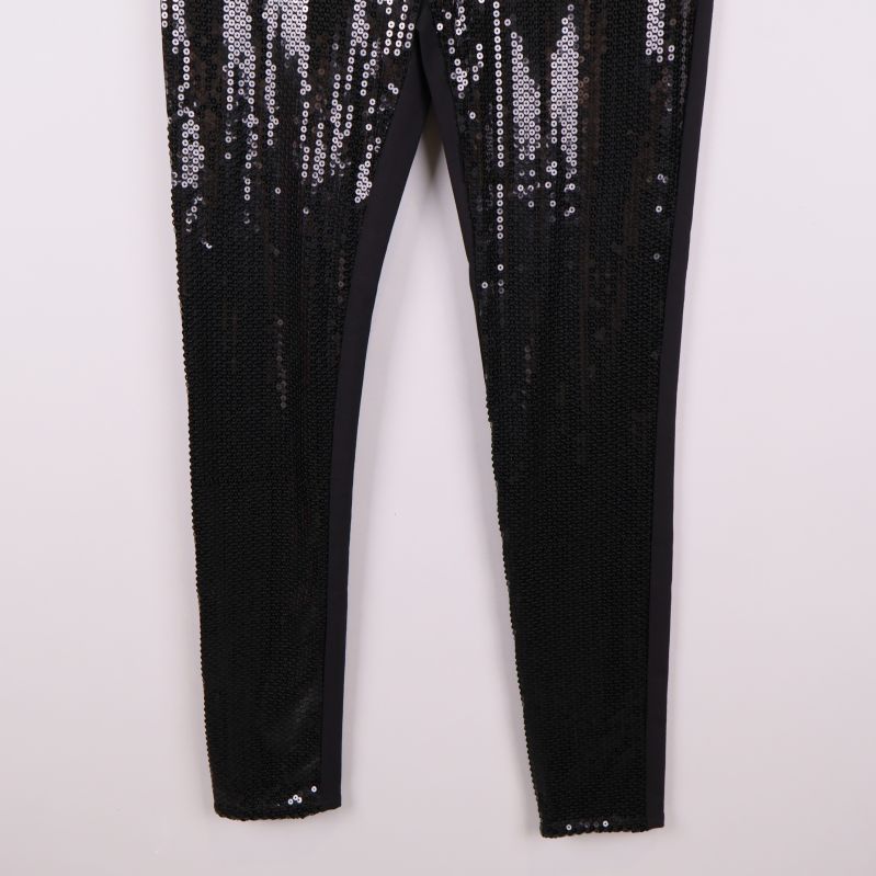 Nedredelen av ben med tättsydda svarta paljetter på tights