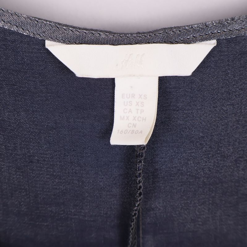 Närbild på storleksetikett med märke H&M och storleksinformation XS