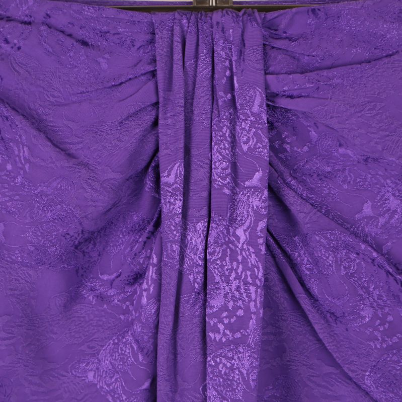 Närbild på draperad detalj framtill på lila kjol