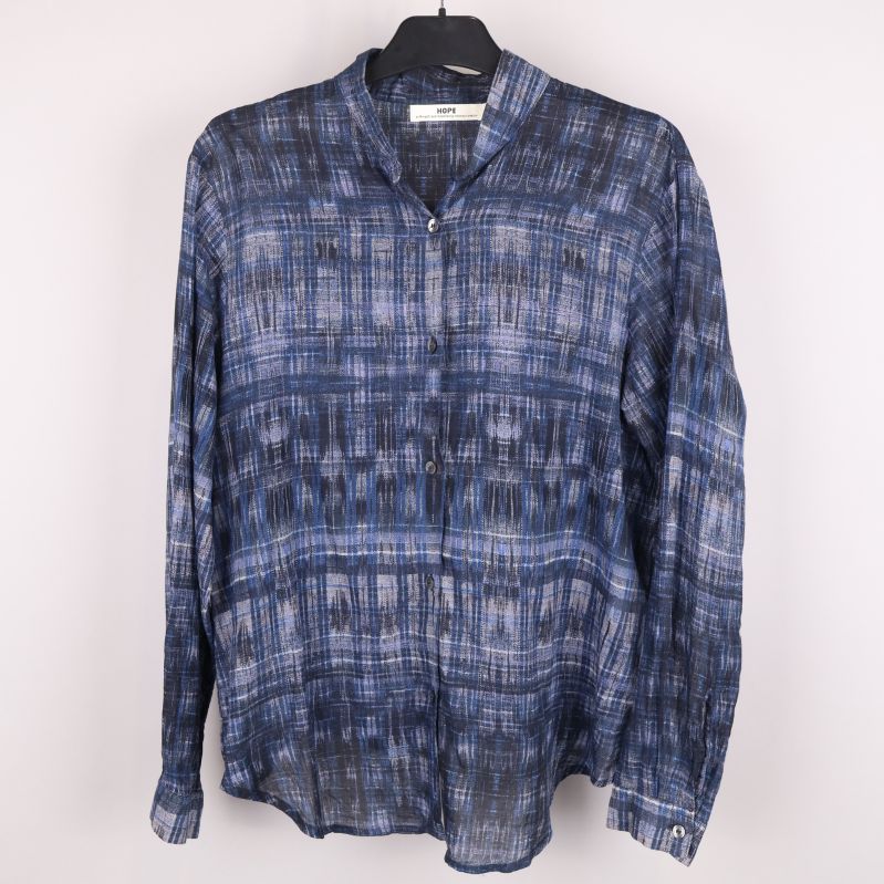 Framsida av blå grafisk HOPE-blus på galge