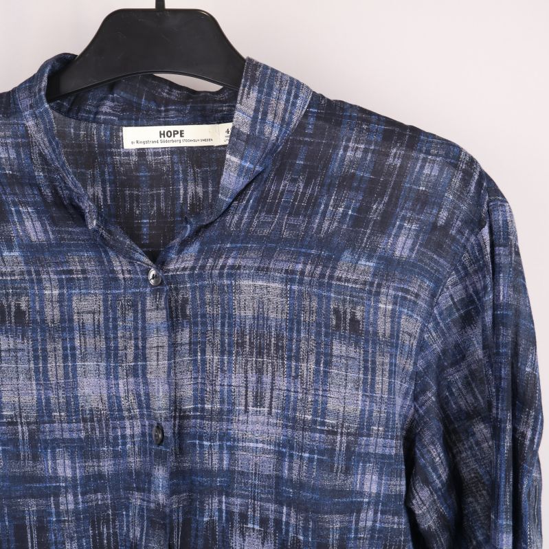 Knappslå och krage på blå grafiskt mönstrad blus