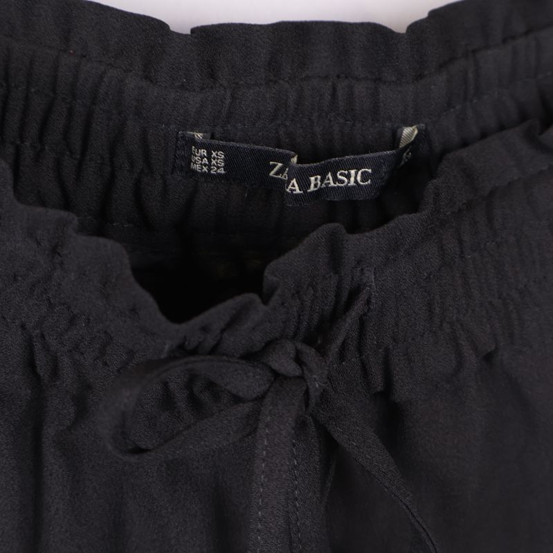 Närbild på midja och dragsko samt etikett ZARA BASIC