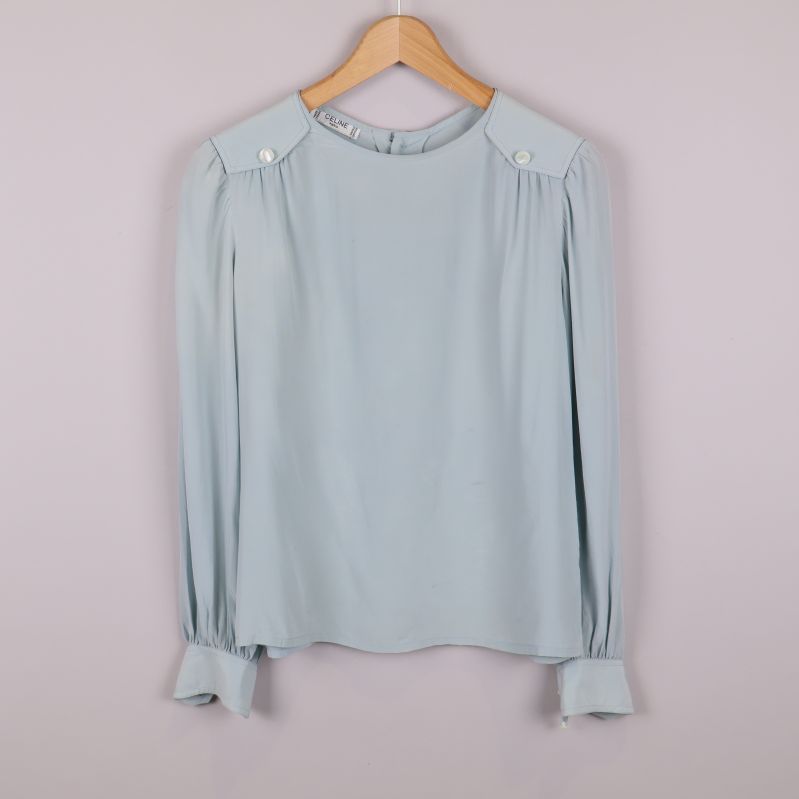 Framifrån av ljusblå blus med pärlknappar på axlar