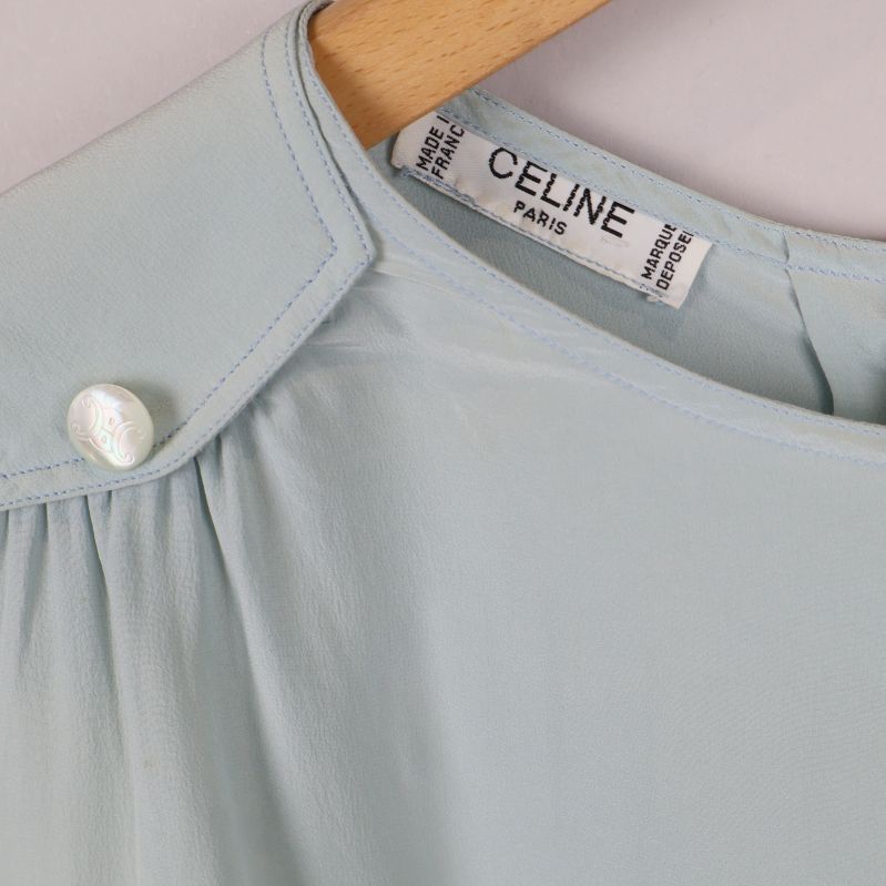 Närbild på axel med pärlknapp och Celine-märke i nacken