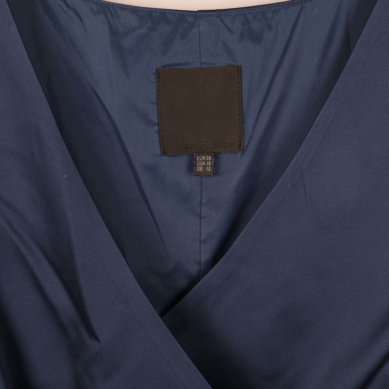 Närbild på V-ringning och etikett på blå klänning