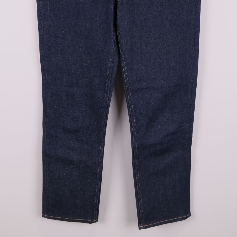 Närbild på benen och fållen av mörkblå jeans