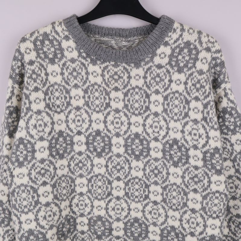 Närbild av halsringning och mönster på stickad tröja