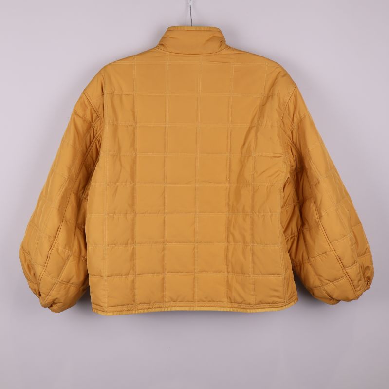 Quiltad jacka i gul nyans fotograferad bakifrån