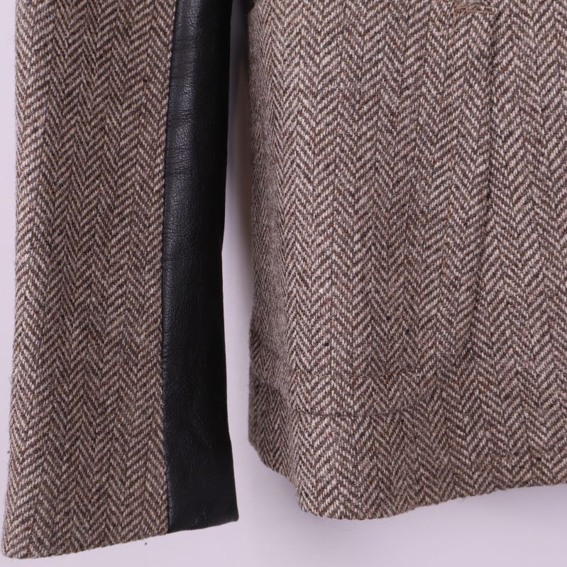 Närbild på blazer med fiskbensmönster och svart skinnärm