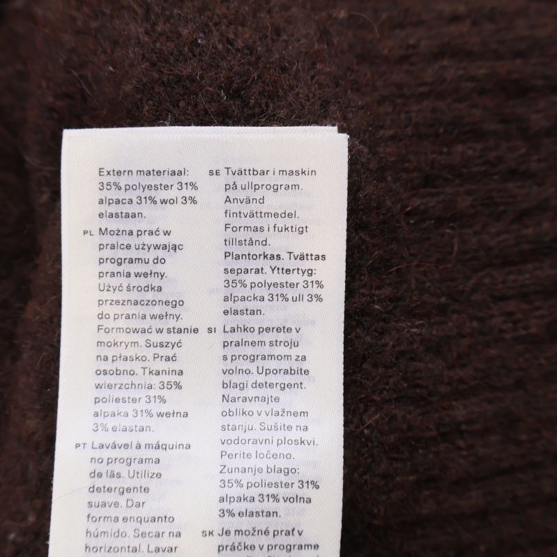 Materialetikett med fiberinnehåll på brun cardigan