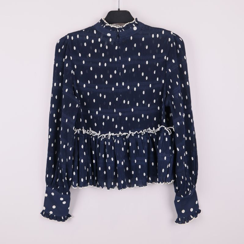 Baksida av blå prickig blus med volanger och lång ärm