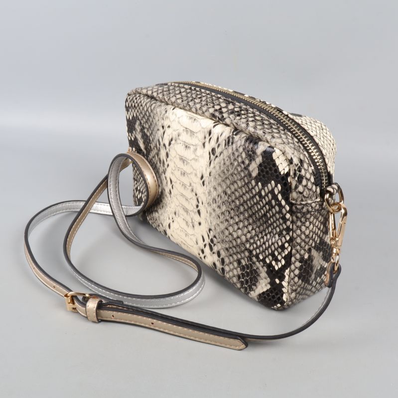 Närbild på väska med gulddetaljer och präglad nyckelring