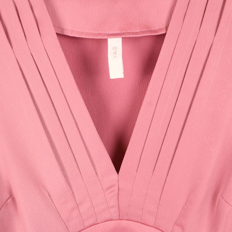 Närbild på plisserad V-ringning och etikett Y.A.S