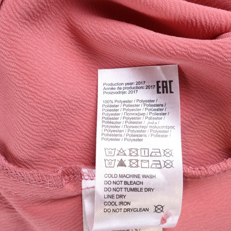 Tvättrådsetikett visar 100% polyester och skötselanvisningar