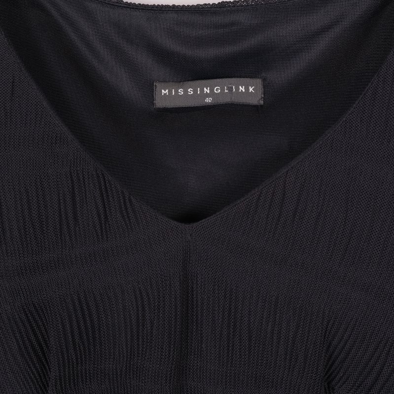 Närbild på klänningens v-ringning och etikett Missing Ink