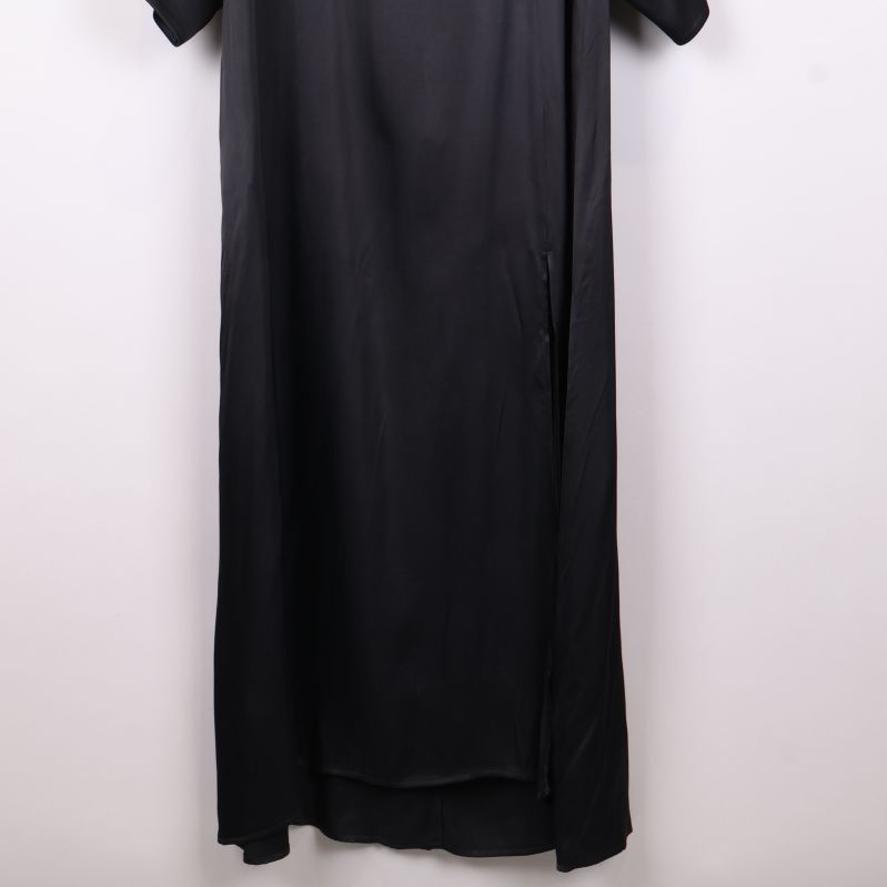 Närbild på nederdelen av svart långklänning med slits