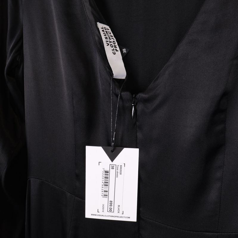 Närbild på klänningens etikett med varumärket Visual Clothing Project