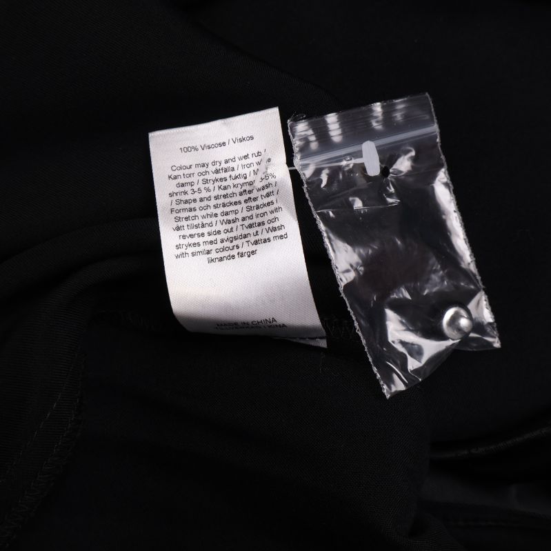 Materialetikett visar 100 procent viskos på svart tyg