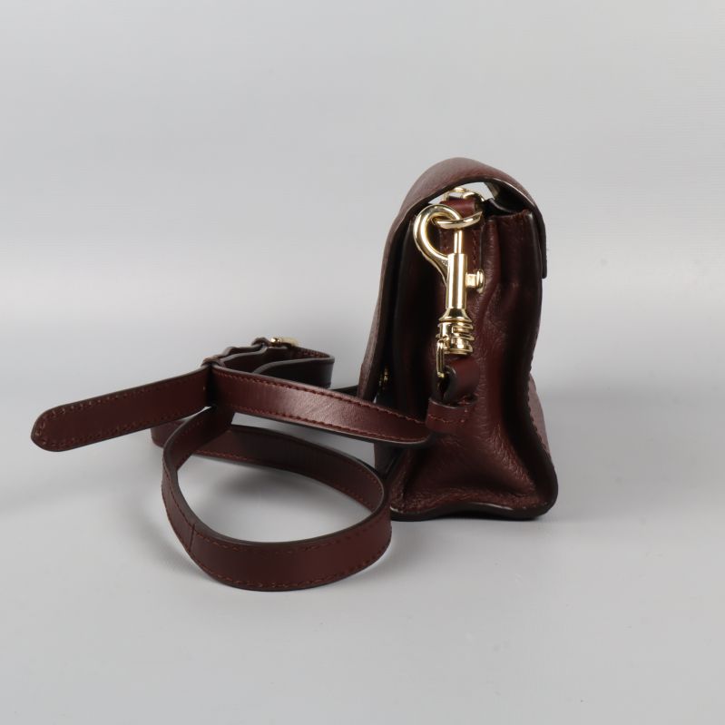 Väskans sida med guldfärgat spänne och rem