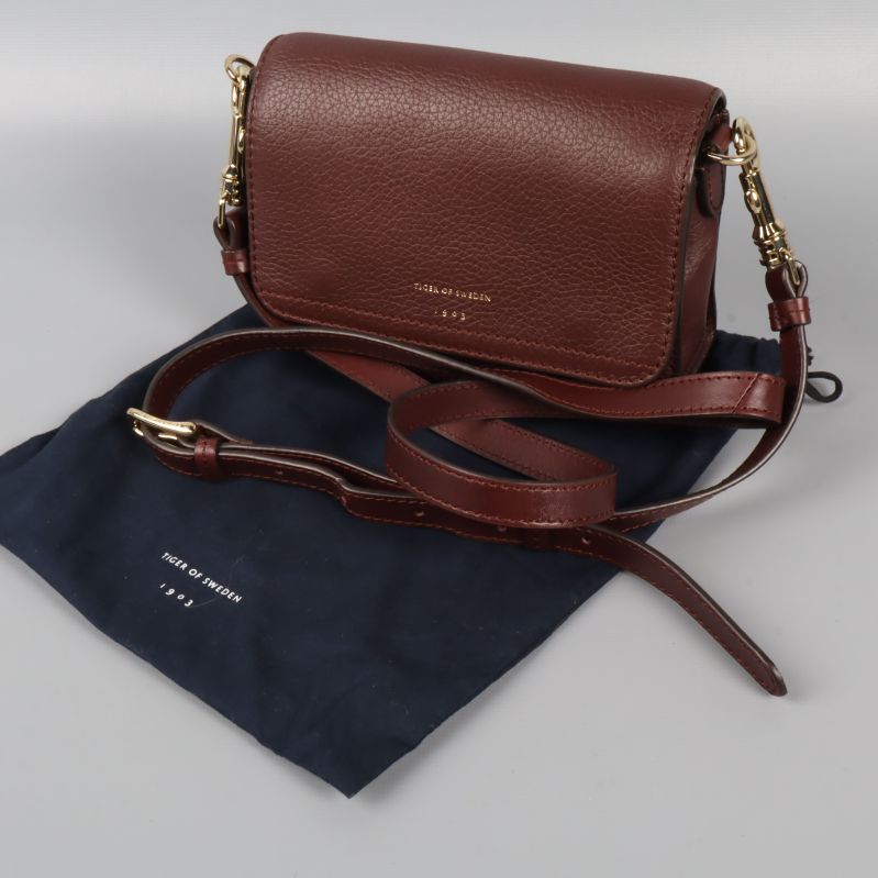 Vinröd läderväska med gulddetaljer och justerbar rem