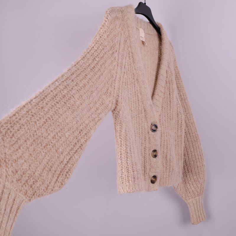 Beige stickad kofta i sned vinkel med vida ärmar