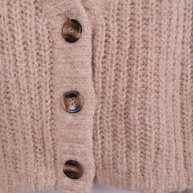 Närbild på bruna knappar på beige stickad kofta