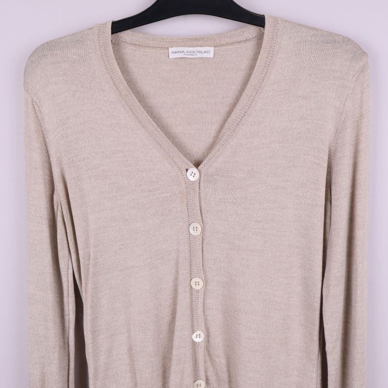 Övre del av beige kofta med v-ringning och knappar