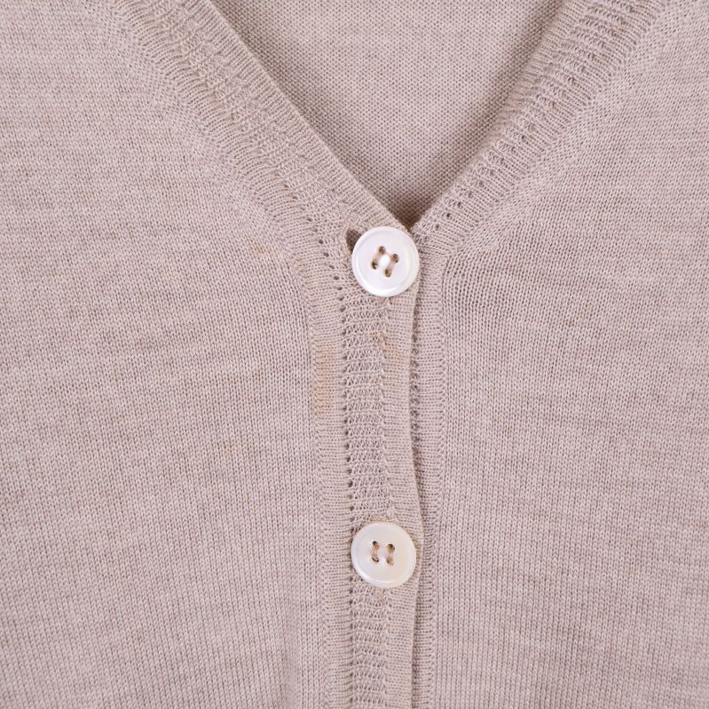 Närbild på koftans vita knappar och stickstruktur