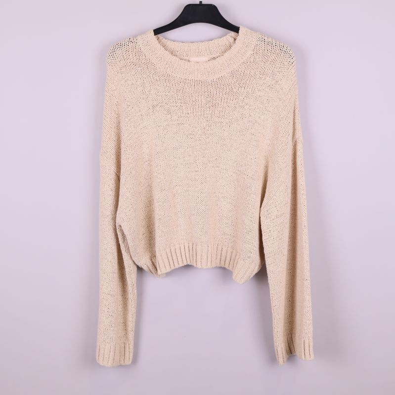 Stickad beige tröja upphängd framifrån