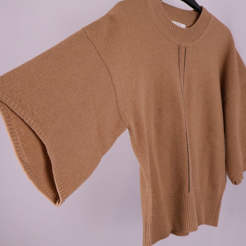Närbild på ärm och sidosöm på beige stickad tröja