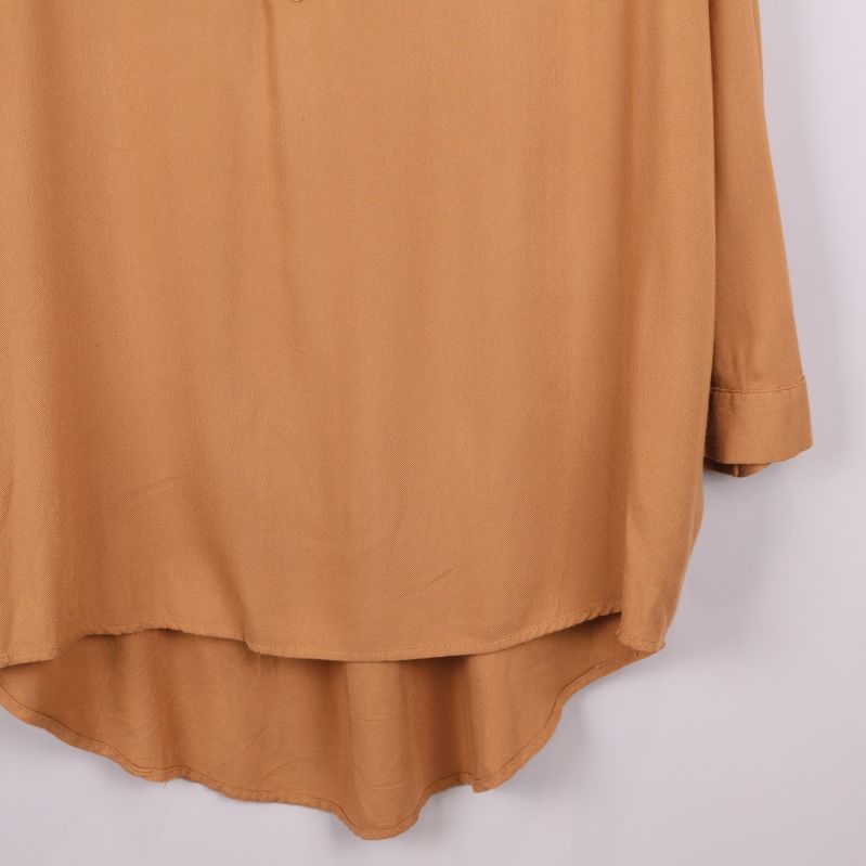 Närbild på den rundade nederdelen av skjortan