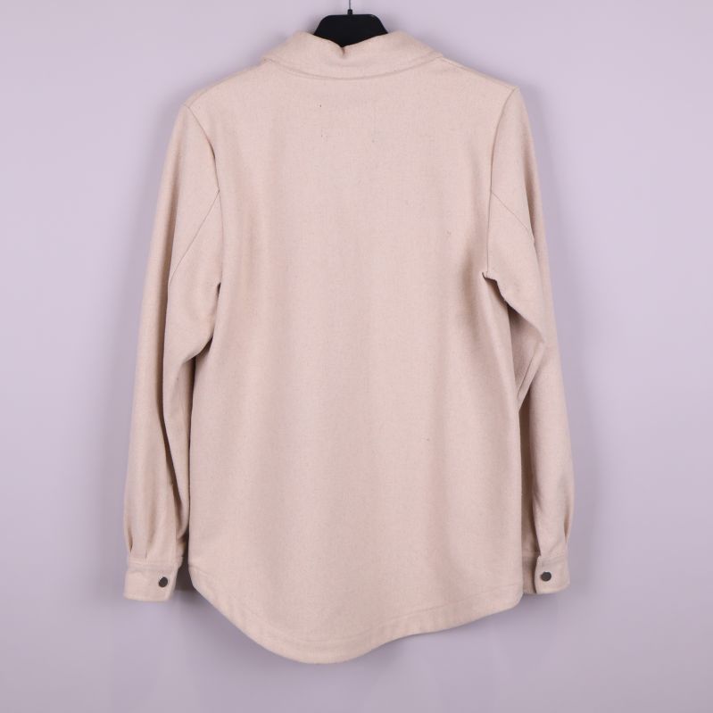 Baksidan av beige overshirt visas upp hängande