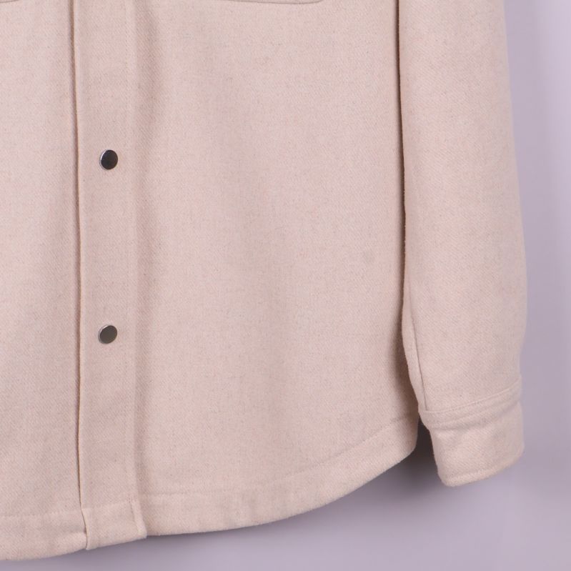 Närbild på knappstängning fram på beige overshirt
