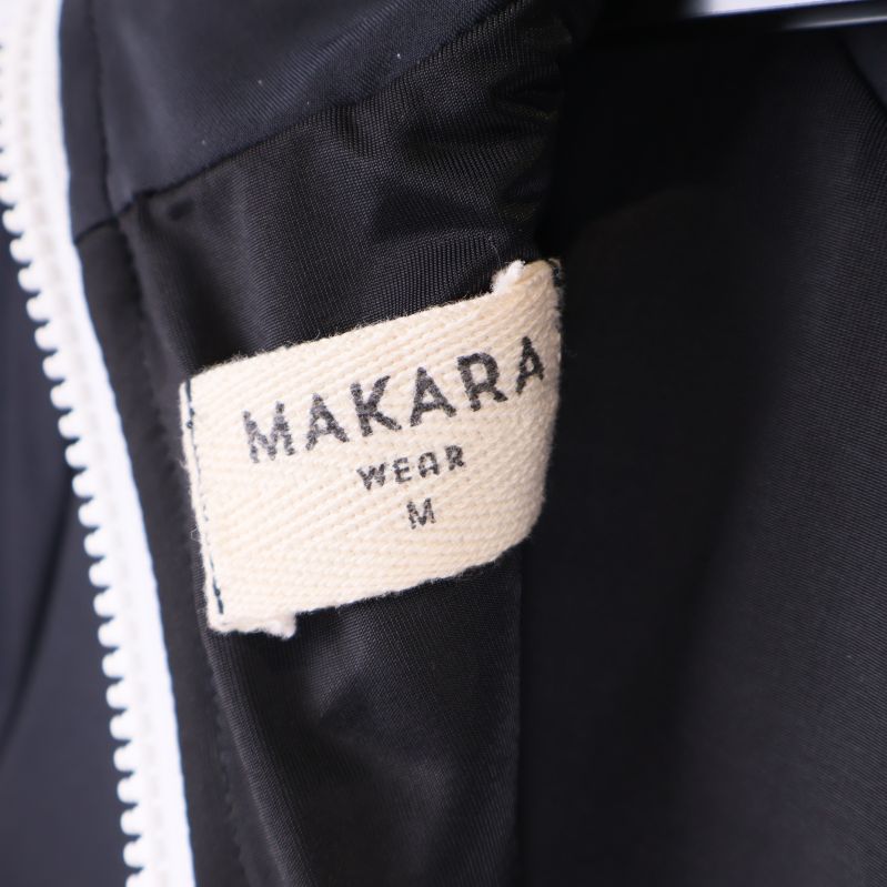 Närbild på etikett med Makara logotyp och storlek M