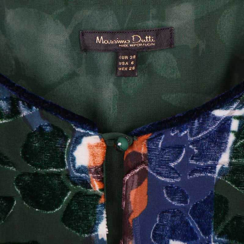 Närbild på Massimo Dutti-etikett och knappdetalj i halsringningen