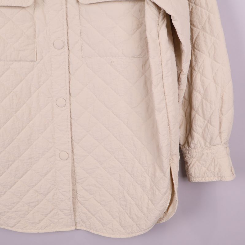 Nedre delen av quiltad beige overshirt med rundad kant