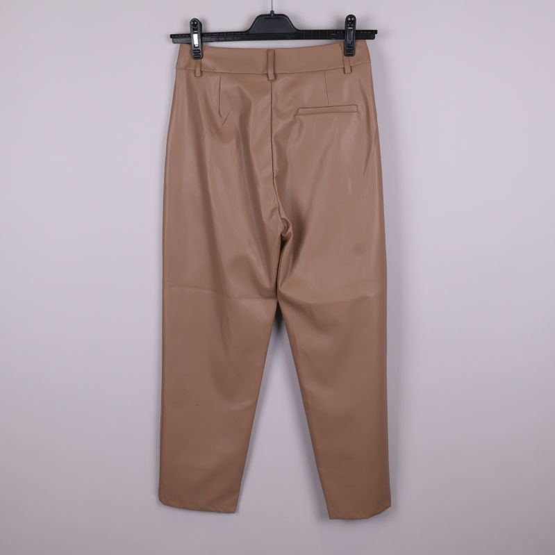 Beiga byxor i skinnimitation upphängda bakifrån