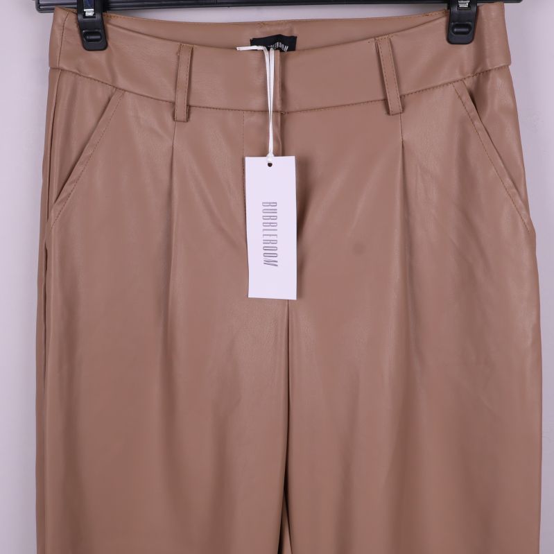 Detaljbild av överdelen och fickor på beiga byxor