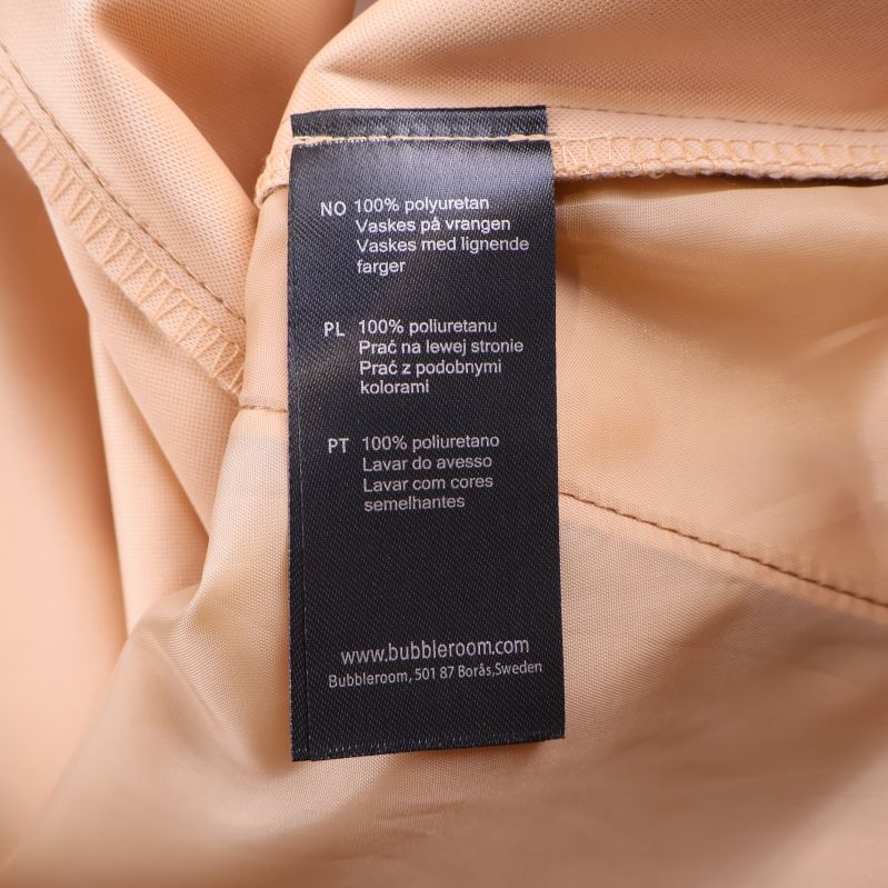 Materiallapp med texten 100% polyuretan på beige tyg