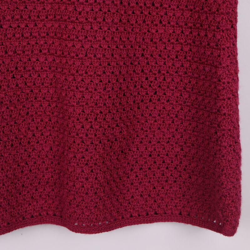 Nederkant av mörkröd stickad kjol i närbild