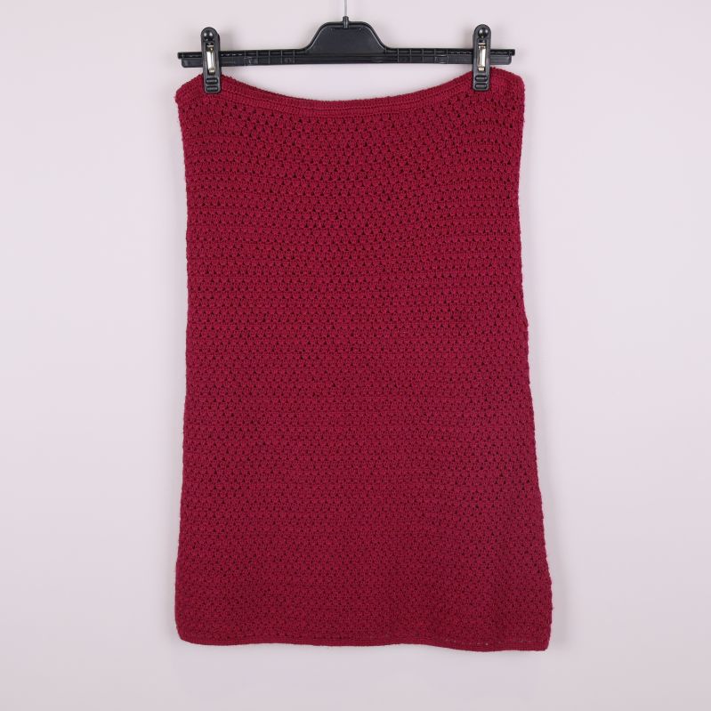 Stickad mörkröd kjol sedd bakifrån mot ljus bakgrund