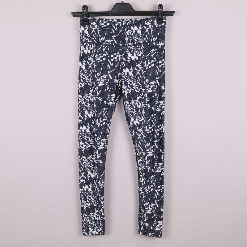 Framsida av svartvita mönstrade träningstights på galge