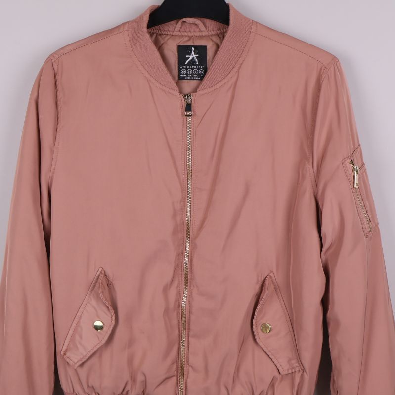 Närbild av fickor och dragkedja på gammelrosa bomberjacka